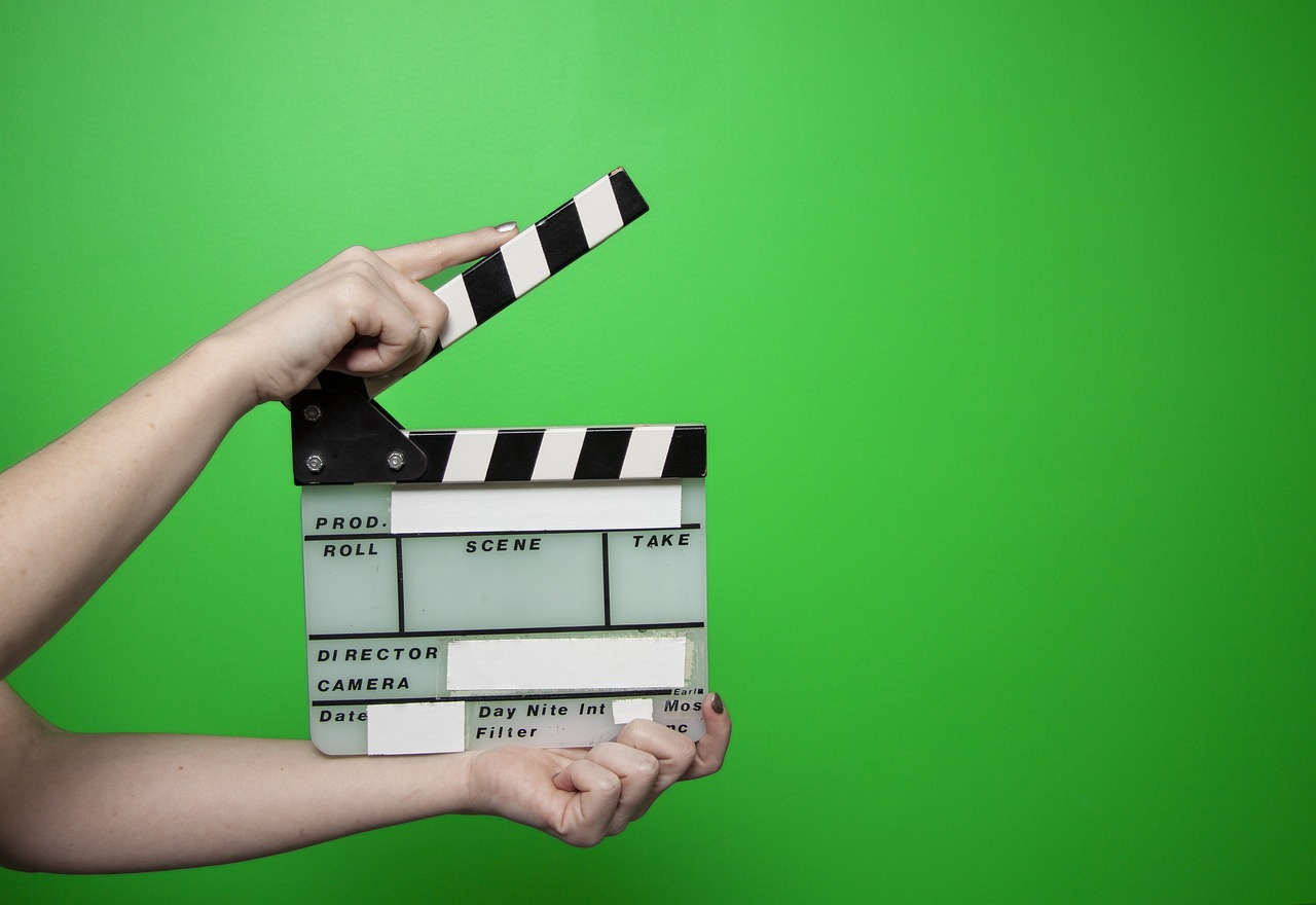 A film clapper in front of a green screen