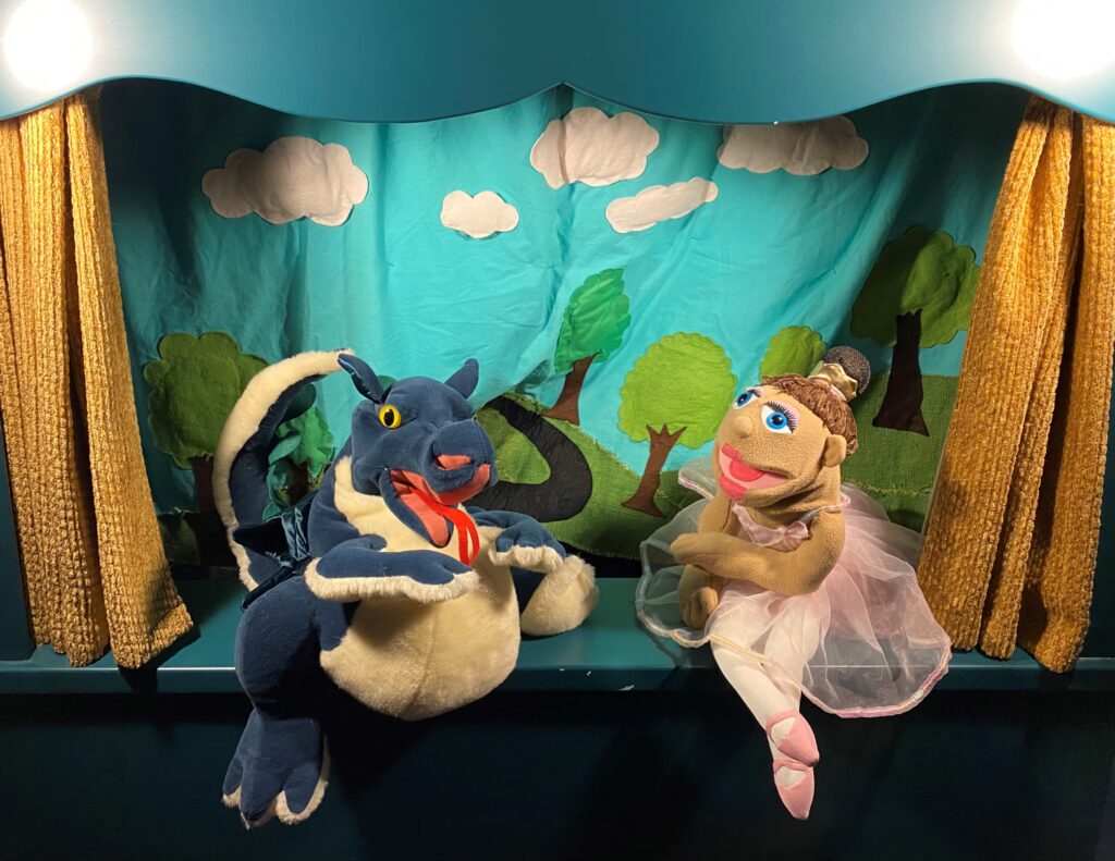 A Dragon and ballet dancer puppet pose on a puppet stage