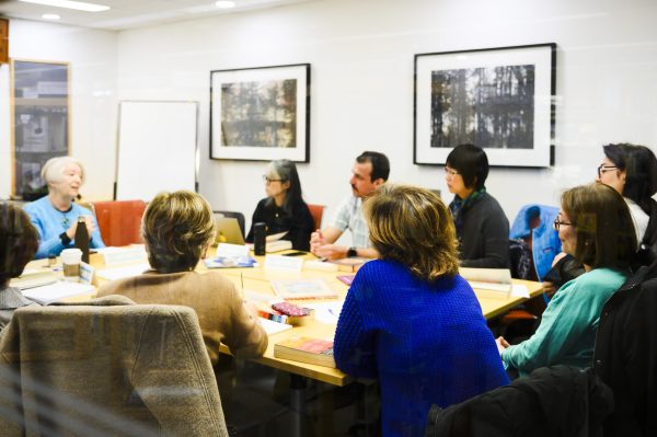 a group sit around a table listening to the discussion leader