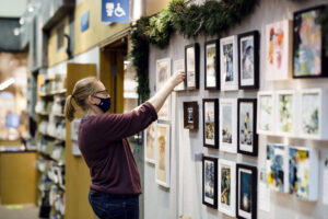 A staff member hangs art in the Library's gallery space.