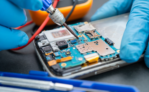 two gloved hands repair a cell phone using a pointed tool.