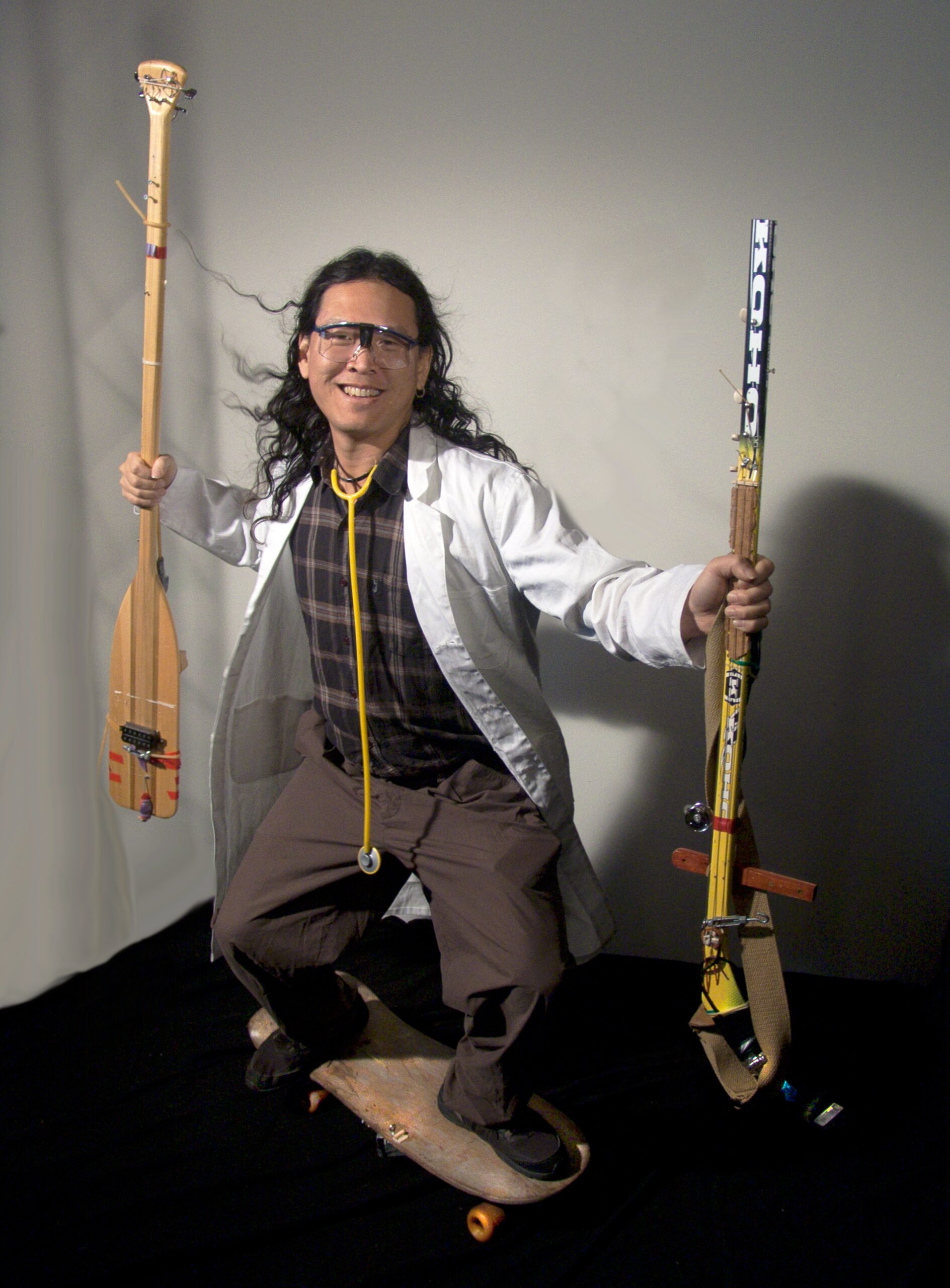 A man holds instruments made out of a hockey stick and boat paddle