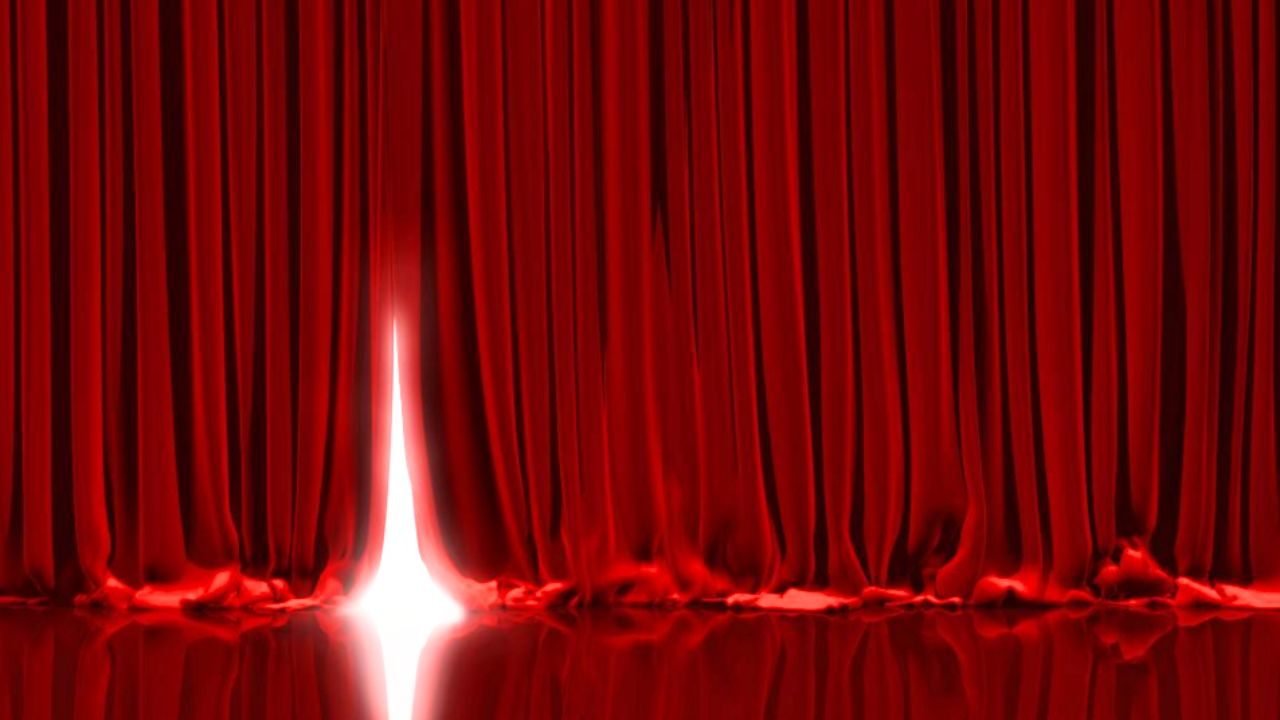 Light shining behind a red stage curtain.