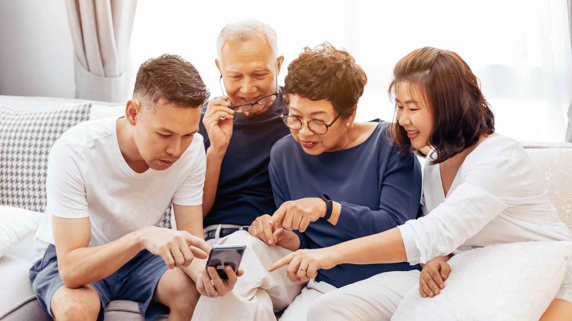 Two older adults are being shown something on a cellphone by two younger adults.