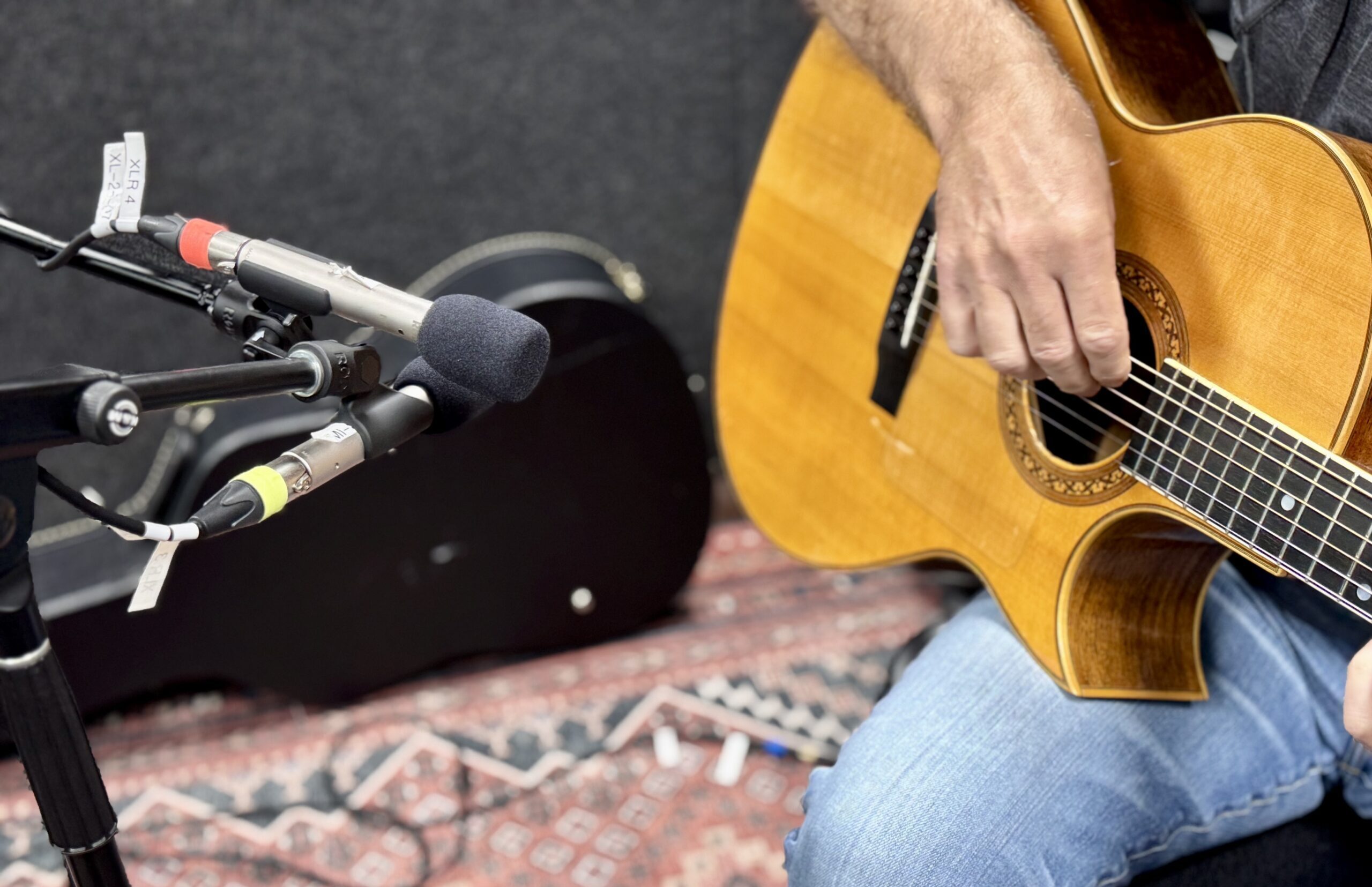 Two RODE NT5 microphones point toward a person playing an acoustic guitar.