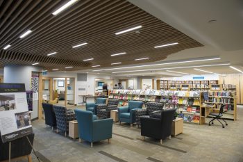 Comfy armchairs in a few different shades of blue are gathered in the centre of the West Wing. Low bookshelves can be seen in the background.