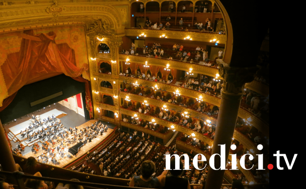 A bird's eye view of a classical concert in a warmly lit opera house. Text "medici.tv" appears in the bottom right.