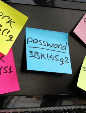 Passwords written on sticky notes attached to a laptop screen.